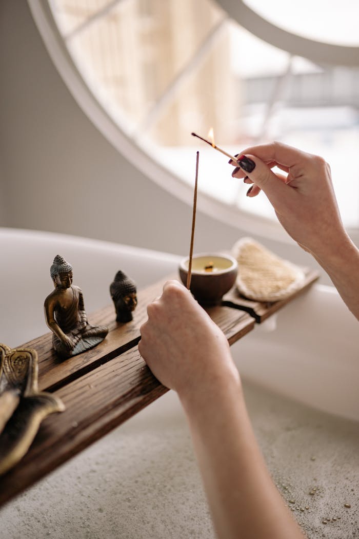 The Art of Drawing Readers In: Your attractive post title goes here Elegant hand lighting incense in a peaceful bath setting with Buddha statues and candles.